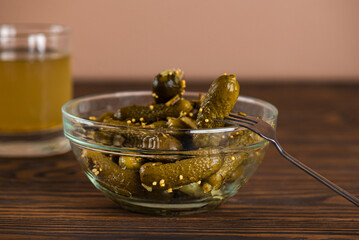 Pickled gherkins with spices in a glass bowl with cucumber juice or brine.