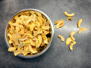 Dried apple slices in metal bowl on gray kitchen table