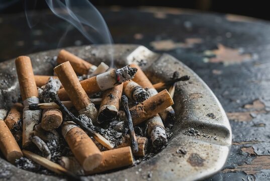 Close up macro photography of pile of dirty cigarette butts and ash in ashtray showing addiction concept