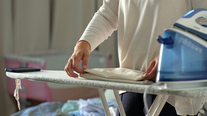Hands neatly folding clothes after ironing, organized and precise, close-up view of domestic...