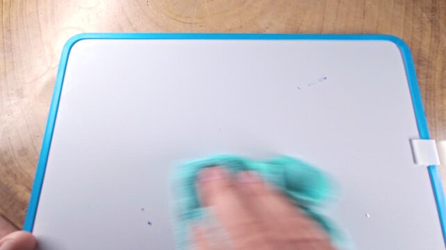 Person's hand cleaning a whiteboard, erasing a handwritten list of investment options including crypto