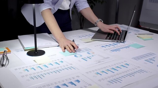 Person analyzing financial data, reviewing business analytics reports, using a laptop with charts, and planning corporate strategy with spreadsheets and investment figures
