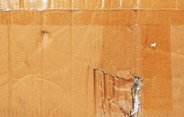 Texture of damaged brown cardboard with traces of tape.