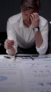 Stressed businessman suffering from overwhelming burnout and work overload, working late into the night, feeling frustrated with deadline pressure in a dark office environment