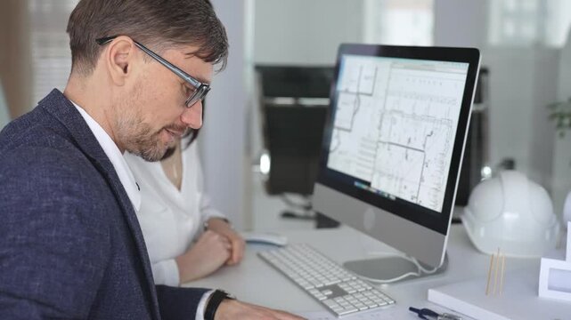 Architecture and engineering team collaborating on project blueprints using computer aided design software in an office. Business and architecture concept