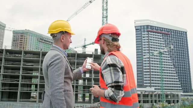 General contractor and subcontractor using smartphone during site inspection