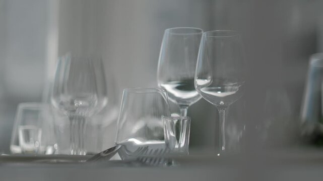Close-up of empty crystal wine glasses and water tumblers arranged on a formal white dinner table