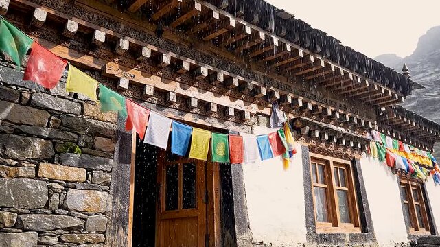 Himalayan stone house with colorful prayer flags rain falling. Looping video suitable for content creator