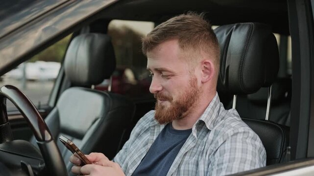 Male driver typing on the smartphone in the car. Slow motion