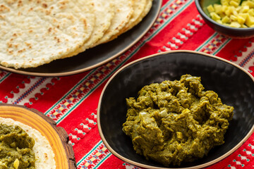 Mustard greens puree, cornmeal flatbreads, chopped ginger. Healthy vegan food. Tablecloth with a red-and-white pattern. © Fotema