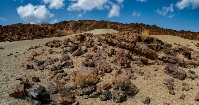 Tenerife, Canary Islands, Spain: red mountains, rock formations and rainbow sand dunes hiking in the Teide National Park with Mount Teide (Pico del Teide) on the background, spectacular landscape