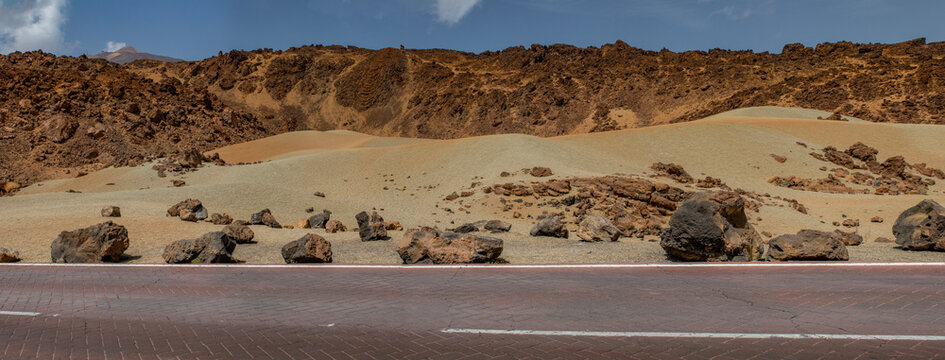 Tenerife, Canary Islands, Spain: red mountains and rainbow sand dunes on the road in the Teide National Park (Parque nacional del Teide) with Mount Teide (Pico del Teide) on the background
