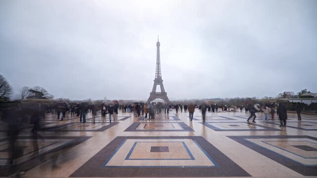 Hyperlapse of Eiffel Tower at Trocadero plaza in Paris with neoclassical architexture. Crowds of tourists in motion blur on a cloudy and rainy winter day