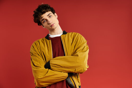 Stylish young man embodies modern fashion against a vibrant red background