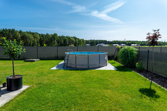 A large expansion pool with a diameter of 3.96 meters, placed on a sheet of plastic on the grass in the garden.