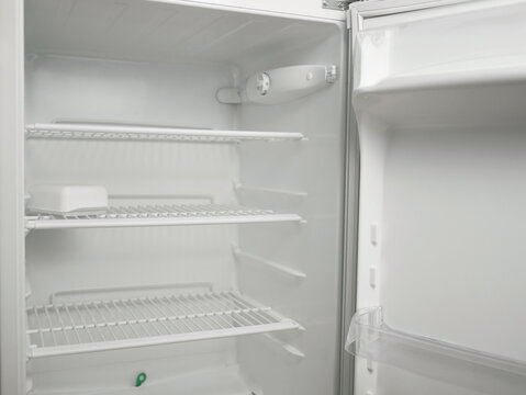 Clean empty fridge interior with adjustable thermostat dial and wire shelves. White modern refrigerator inside view, cold storage concept, minimal kitchen appliance background