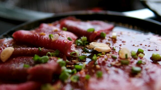 A stack of raw pork chops lies on a black stone slab. The rotating meat reveals juicy cut edges and marbling.