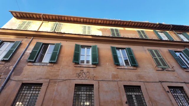 Slow motion macro of historic Roman house facades with ocher walls and wooden shutters.