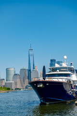 Fototapeta premium Low angle view of a dark blue yacht at a pier with One World Trade Center in the distance.