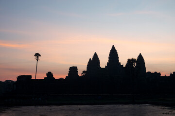 Fototapeta premium Angkor Wat, Cambodia, Sunrise behind the iconic Angkor Wat temple. Silhouette. Reflected in lake