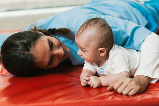 Physiotherapist interacting with a baby lying in prone position during rehabilitation therapy