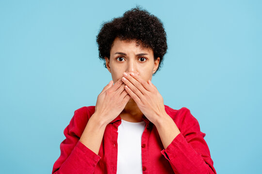 Beautiful African American woman showing silence sign or keeping a secret on blue background