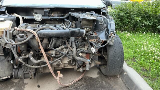The car was seriously damaged as a result of a recent collision and a traffic accident. Close-up of car engine shows a extensive damage to the front as a result of a serious accident.