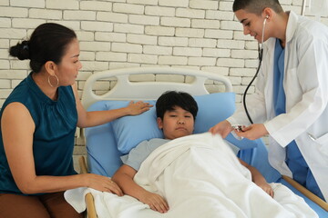Fototapeta premium A single mother is caring for her overweight son who is sick in the hospital. A pediatrician is coming to examine him at his hospital bed. 