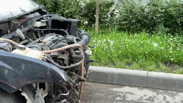 Disassembled car engine, a removed bumper after an accident, shows exposed engine parts and various internal mechanical parts awaiting repair and diagnosis. The front view of the car is disassembled.