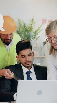 Close up of pleasant satisfied experienced professional male and female engineers in vests and hardhats which previsioning scheme of future construction on computer with qualified purposeful main