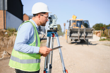 Surveyor using theodolite for land measurement at construction site