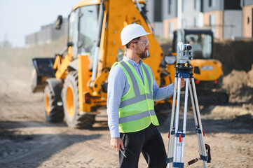 Surveyor using total station at construction site