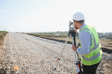 Surveyor using geodetic equipment for road construction measurement