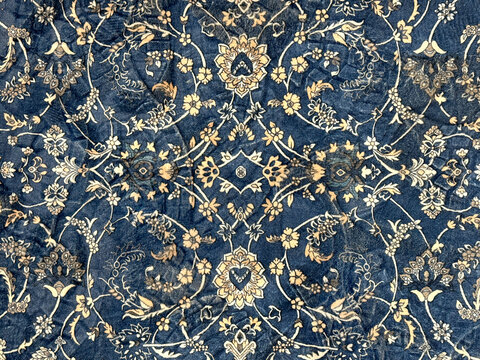 Close up of classic middle eastern Persian rug texture. Engraving and floral ornamental swirls pattern in random blue, beige, and gold color. For moslem prayer mat and decorative rug. Middle East