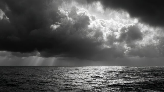 A dramatic, monochromatic seascape with dark, ominous clouds and a sunbeam piercing through, casting a silvery glow on the water. 