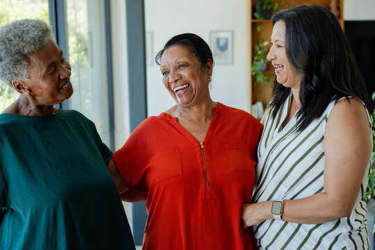 African American seniors and mature woman linking arms laughing in den by glass doors with zipper