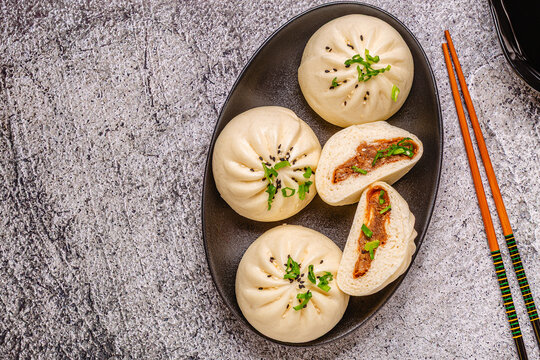 Steamed buns on a dark plate.