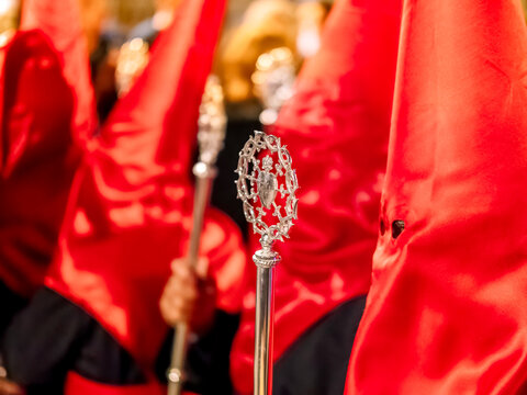 Close-up of red-hooded nazarenos with a silver scepter