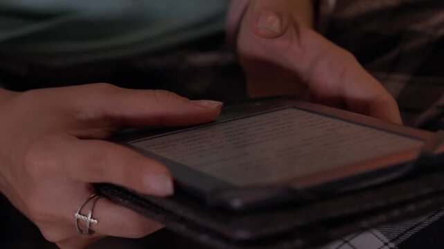Page Turn Detail On Ereader With Soft Teal Display And Leather Case Close Hands, Ring On Finger, Gentle Tap Transitions, Cozy Nighttime Atmosphere For Tech Readers And Story Lovers