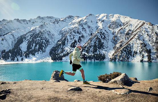Man running at the trail in the winter mountains