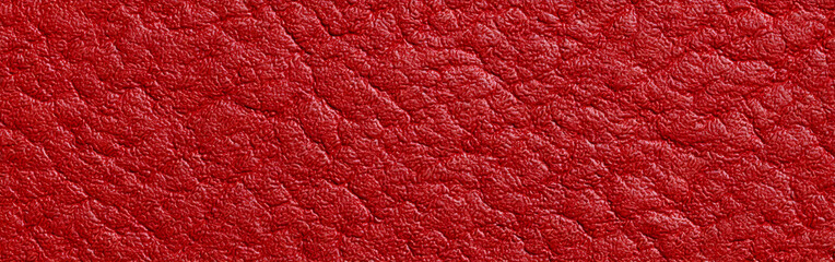 Red textured abstract background. Embossed pattern for wallpaper or surface design. Macro detail of material surface with uneven pattern.