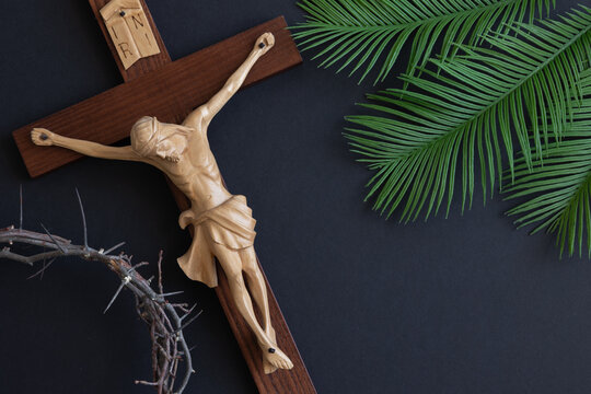 Crucifix, palm branches and crown of thorns close up on a black background