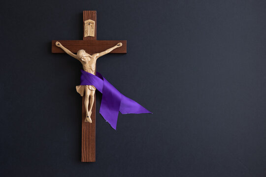 Crucifix with purple ribbon on a black background with copy space