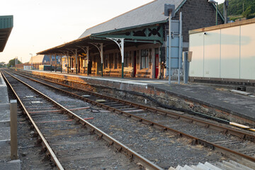 Obraz premium Barmouth ,Wales, 14 june 2023 Peaceful Train Platform At Barmouth Station With Stop Sign, Shelter And Railway Tracks