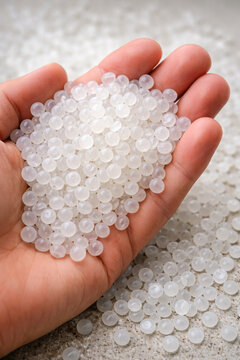 Milchig wei&szlig;e Kunststoffpellets in der Hand als Rohmaterial der Plastikindustrie