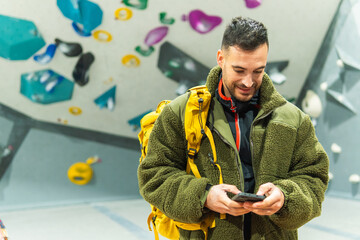 Man checking smartphone at indoor bouldering gym © ALIDA
