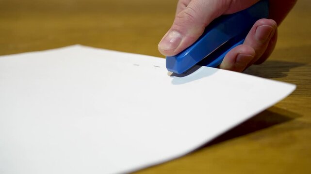 Close-up of office stapler binding sheets of paper with loud metallic click sound, stationery ASMR
