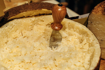 Artisan Parmesan Cheese Wheel Being Scraped With Wooden-Handled Cheese Knife In Market
