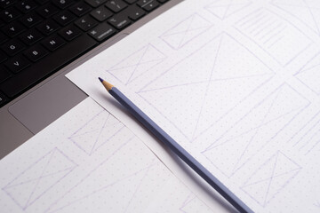 Hand-Drawn Website Wireframes Close-up on Dot-Grid Paper with Pencil and Laptop Keyboard