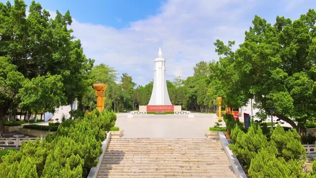 Tree-Lined Plaza with White Monument Tower and Symmetrical Gardens